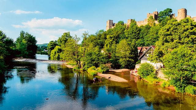 Beautiful calm scene of the River Teme with the Medievil Ludlow castle partially shrouded amongst trees